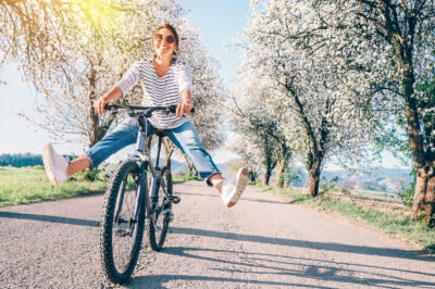 Happy young woman riding a bicycle in the sunshine.